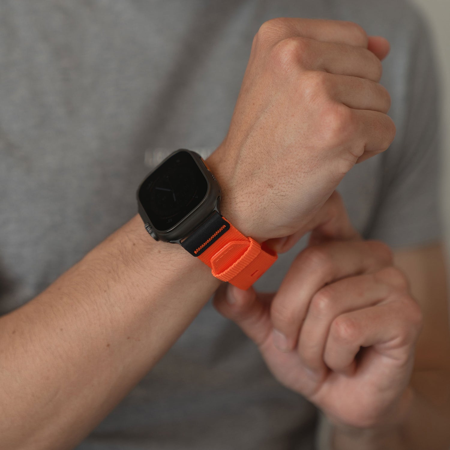 Eine Person mit grauem Hemd passt ihr arktisband Apple Watch Armband "Terra" in Orange (extra breit 24 mm) von arktisband an ihr Handgelenk an.