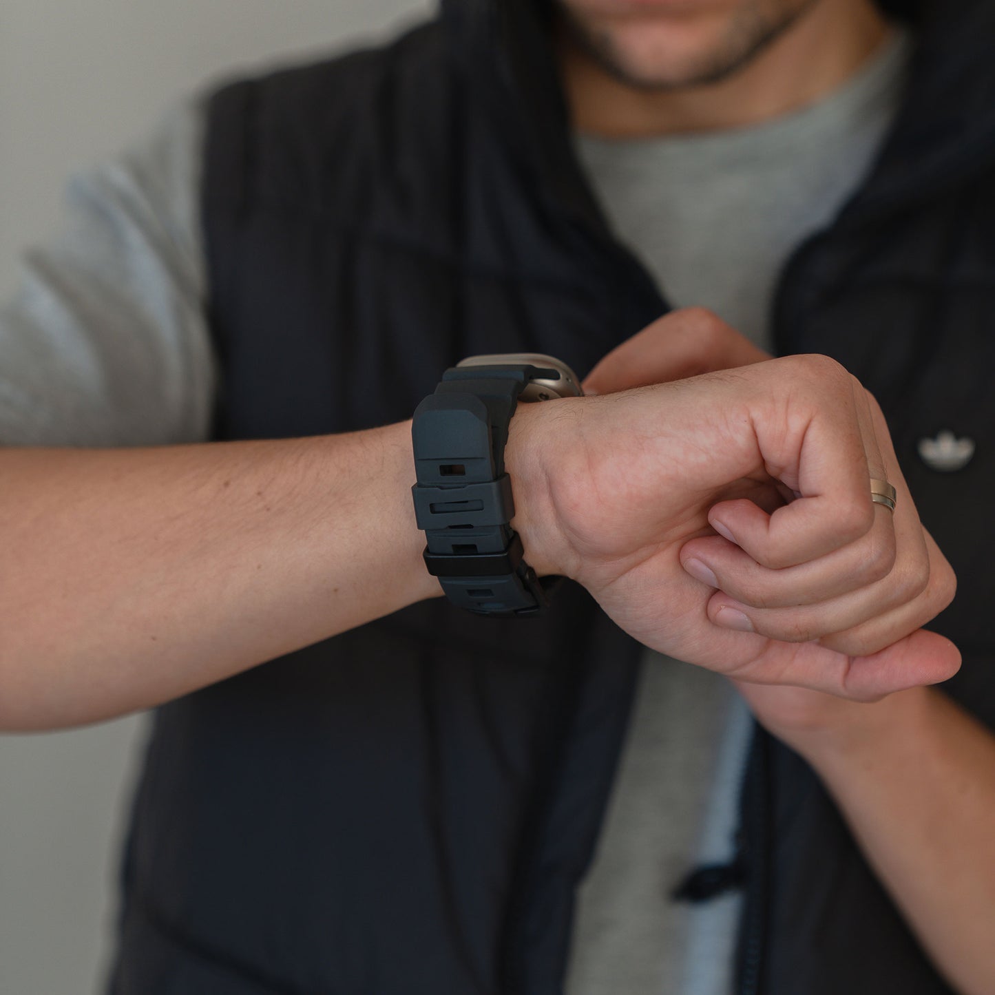 Eine Person in einer Weste kontrolliert ihr arktisband Apple Watch Armband "Flux" von arktisband, das eine sichere und elegante Edelstahl-Schließe am Handgelenk hat.