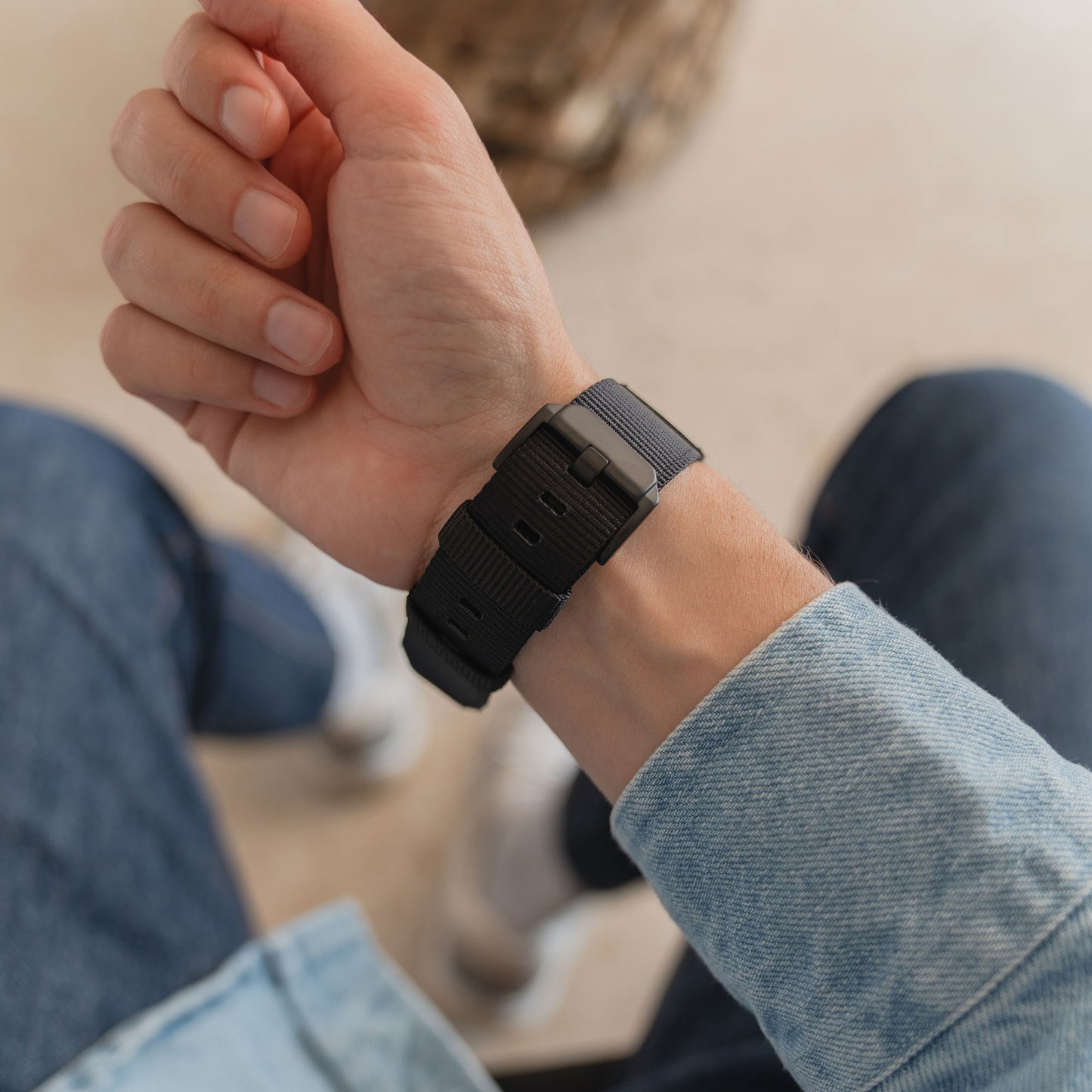 Eine Person trägt ein arktisband Apple Watch Armband "Terra" von arktisband, gestylt mit Blue Jeans und einer hellen Jeansjacke.