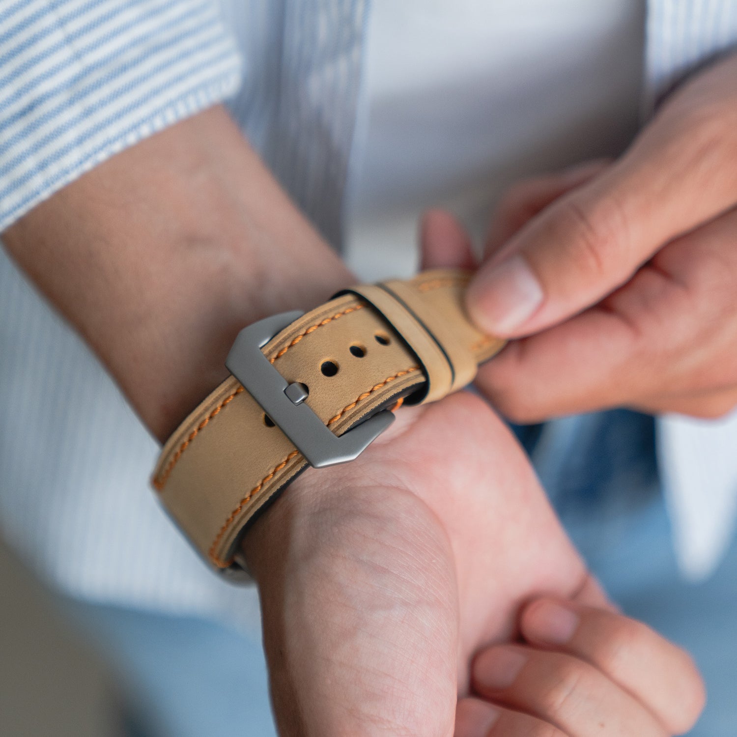Nahaufnahme einer Person, die das Arktisband Apple Watch Ultra PALERMO GRANDE Lederarmband in Beige mit einer Schließe aus 316L-Edelstahl befestigt, ideal für die Apple Watch Ultra.