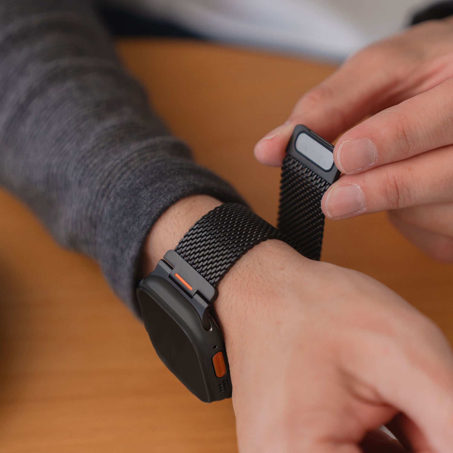 Eine Person befestigt ein Arktisband Apple Watch Milanaise Armband "Bold SE" Special Edition schwarz Smartwatch an ihrem Handgelenk.