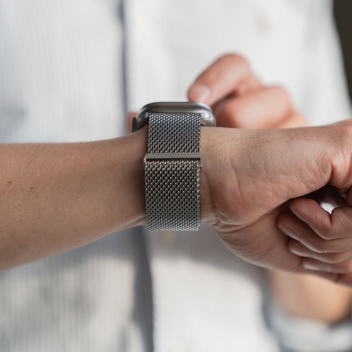 Der Träger des arktisband Apple Watch Ultra Milanaise Armband "Bold" von arktisband mit einer stilvollen Bandbreite von 26 mm tippt auf seinen Bildschirm und verbindet so Eleganz und Funktionalität für anspruchsvolle Träger.