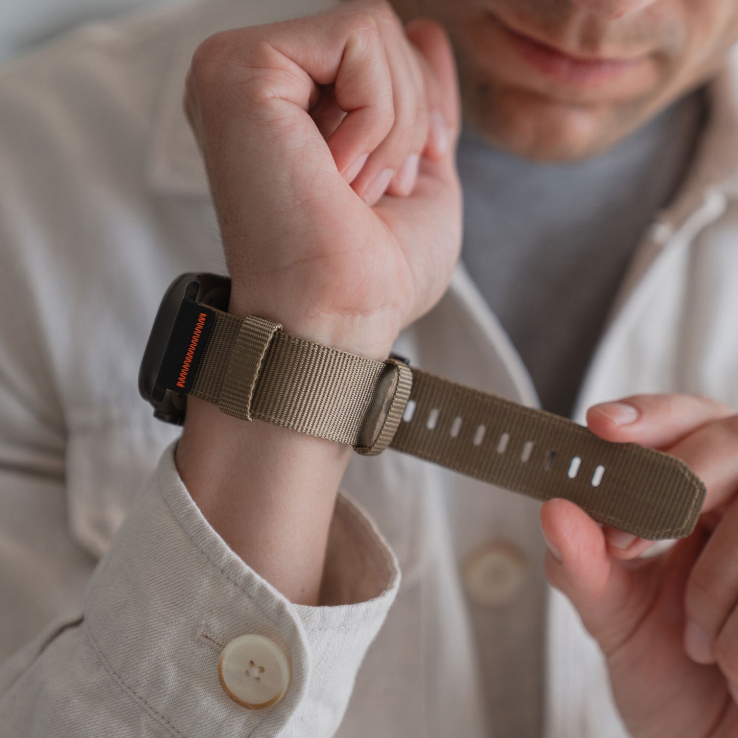 Die Person befestigt das arktisband Apple Watch Armband "Terra" von arktisband (extra breites 24 mm Nylon) an ihrem Handgelenk und trägt ein helles Hemd.