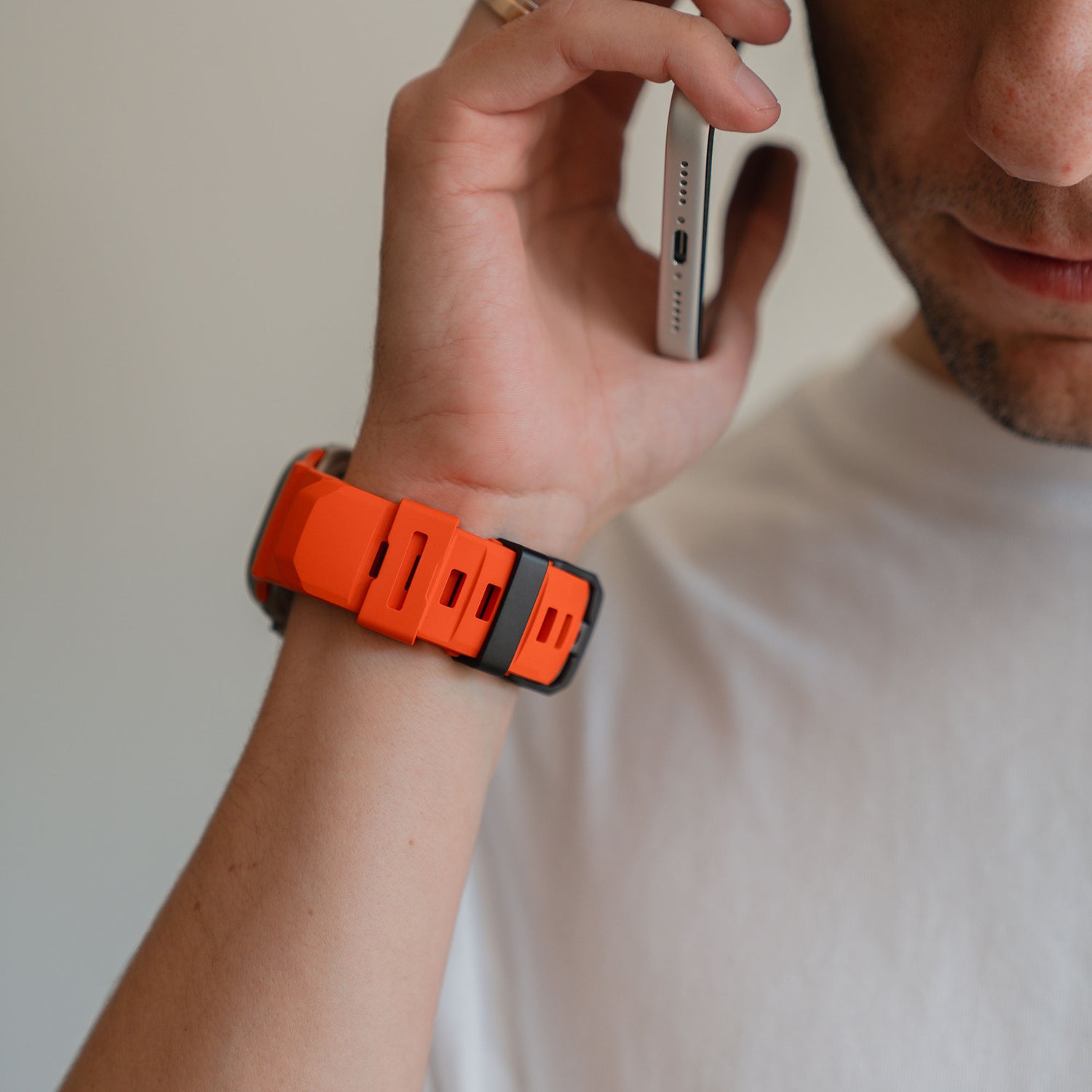 Eine Person in einem weißen Hemd telefoniert, sie trägt ein orange-schwarzes Arktisband Apple Watch Armband "Flux" mit Edelstahl Schließe am Handgelenk.
