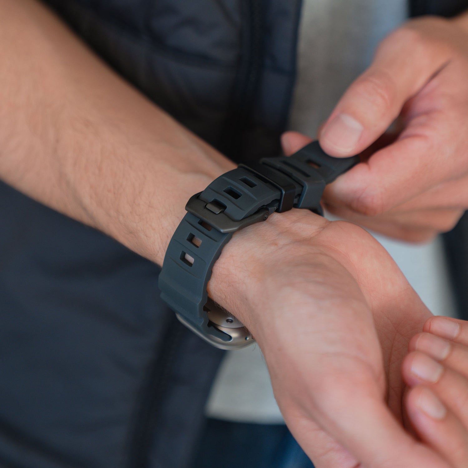 Eine Person befestigt das schwarze Arktisband Apple Watch Armband "Flux" mit Edelstahl-Schließe an ihrem Handgelenk.