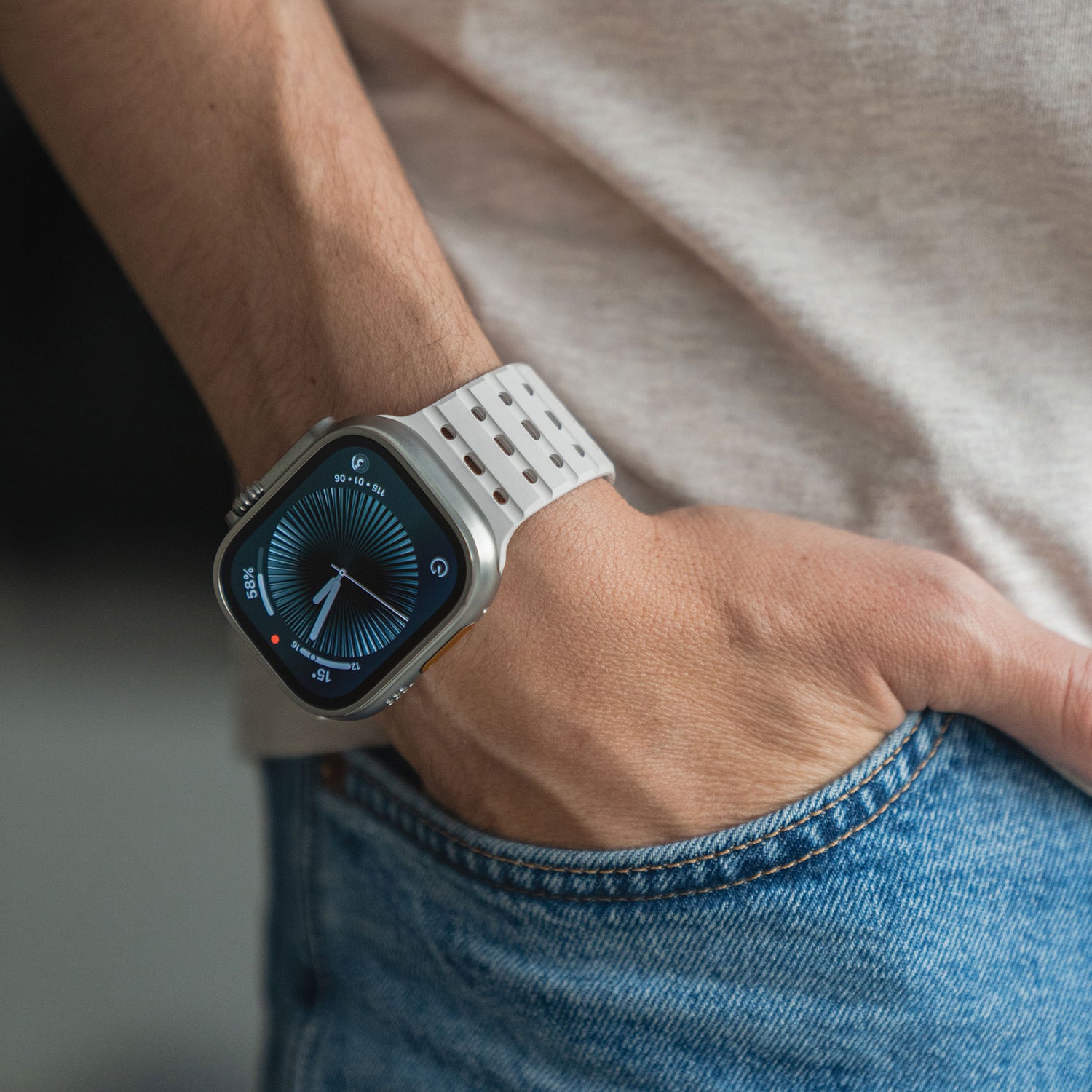 Eine Person in hellem Hemd und Bluejeans hat die Hand in der Tasche und trägt ein magnetisches Silikonarmband „Power“ der Apple Watch mit blauer Analoganzeige.