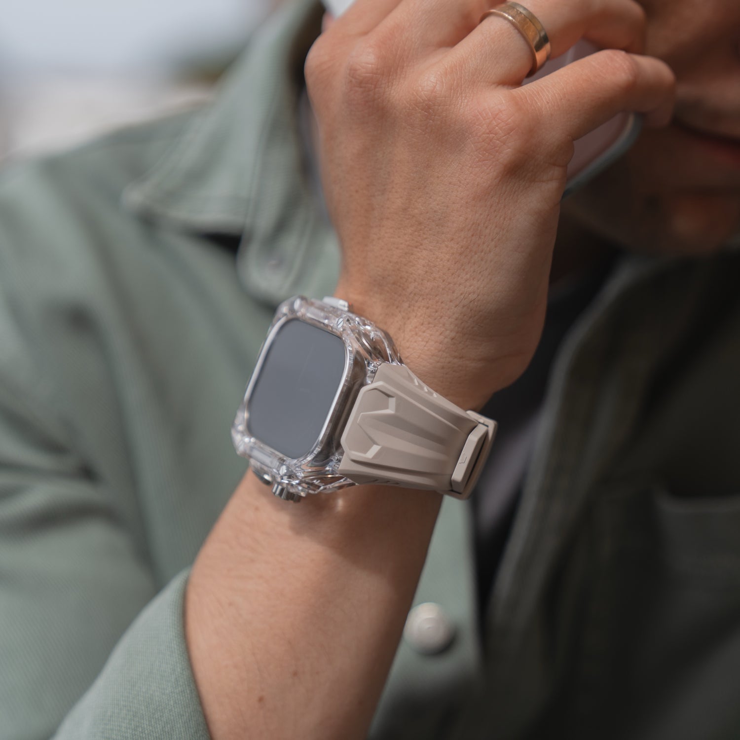 Nahaufnahme einer Person, die das arktisband Apple Watch Armband "Armor Fusion" mit einem beigen Silikonband trägt und ein Telefon an ihr Ohr hält.