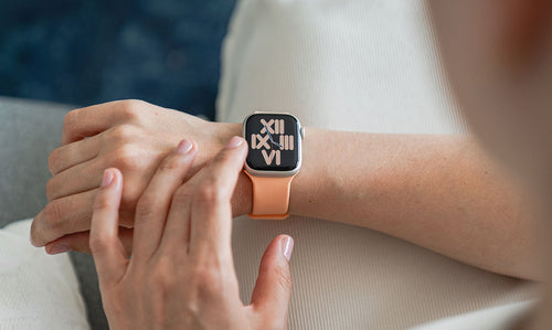 Eine Frau trägt ein pfirsichfarbenes Apple Watch Silikonarmband.