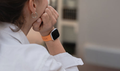Orangenes Apple Watch Silikonarmband an einem Handgelenk.