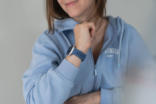 Blaues Apple Watch Armband am Handgelenk mit herbstlichem Outfit.
