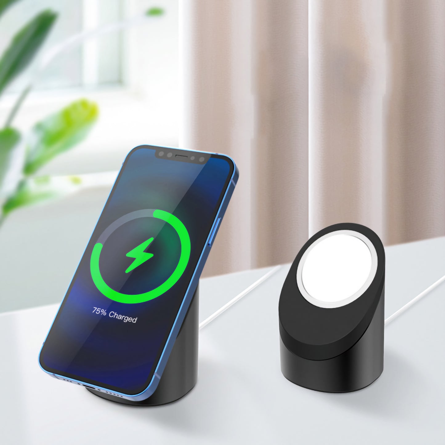 Ein arktis MagSafe NightStand hält ein Smartphone, das zu 75% geladen ist, während eine leere iPhone-Ladestation in der Nähe auf einem weißen Tisch steht.