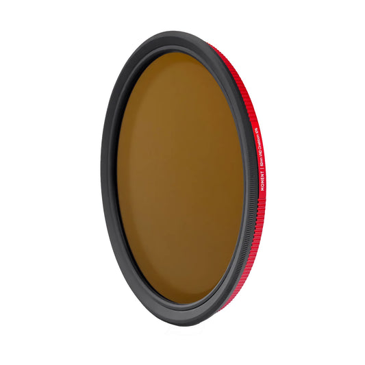 Der MOMENT 67mm Variable ND (2-7 Stop) & CineBloom 10 Filter hat ein kreisförmiges Design mit einem rot umrandeten Rand und braun getöntem Glas, isoliert auf Weiß dargestellt.