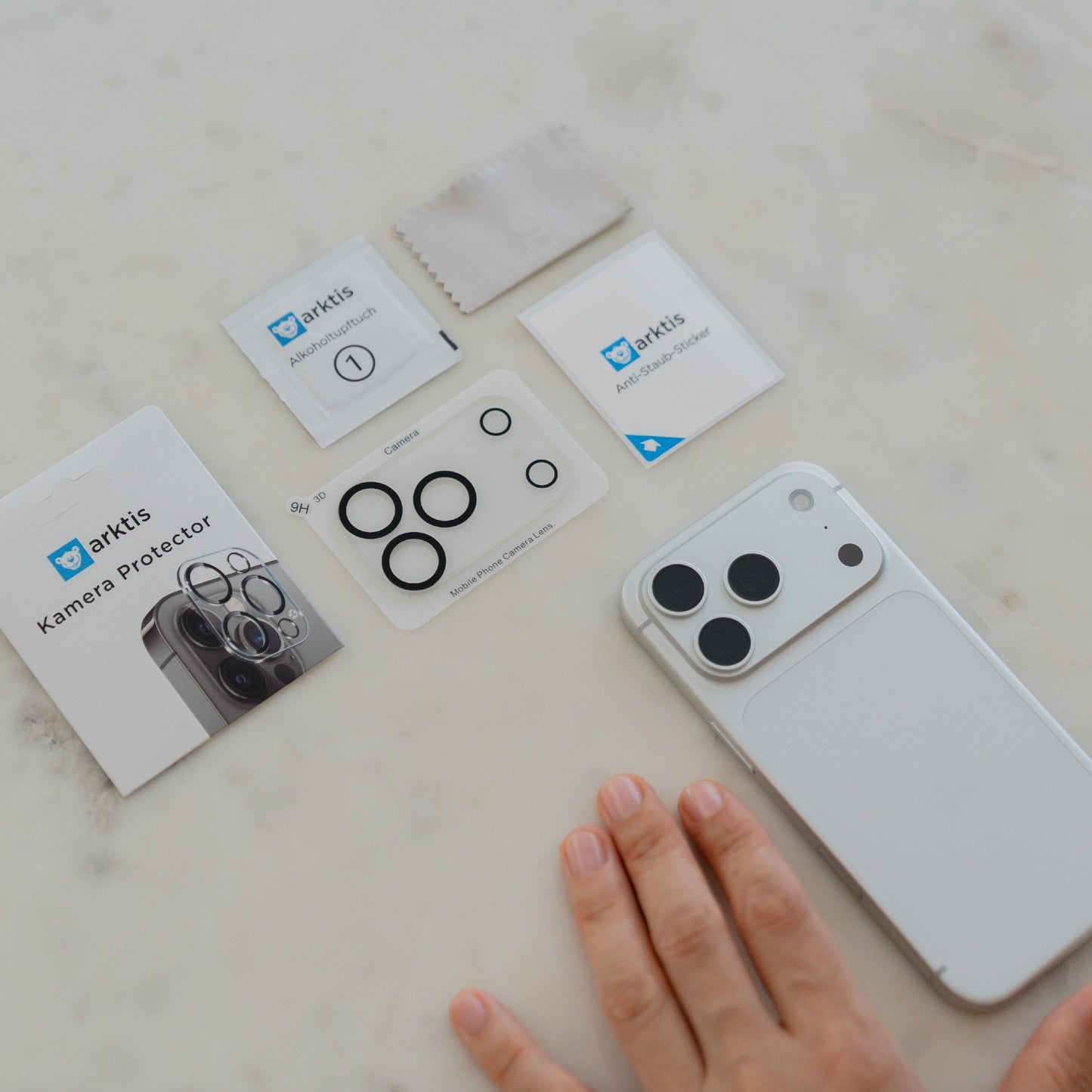 Eine Hand neben einem arktis iPhone 17 Pro Max Kamera Protector von arktis zeigt den Protector neben dem Kameraobjektiv.