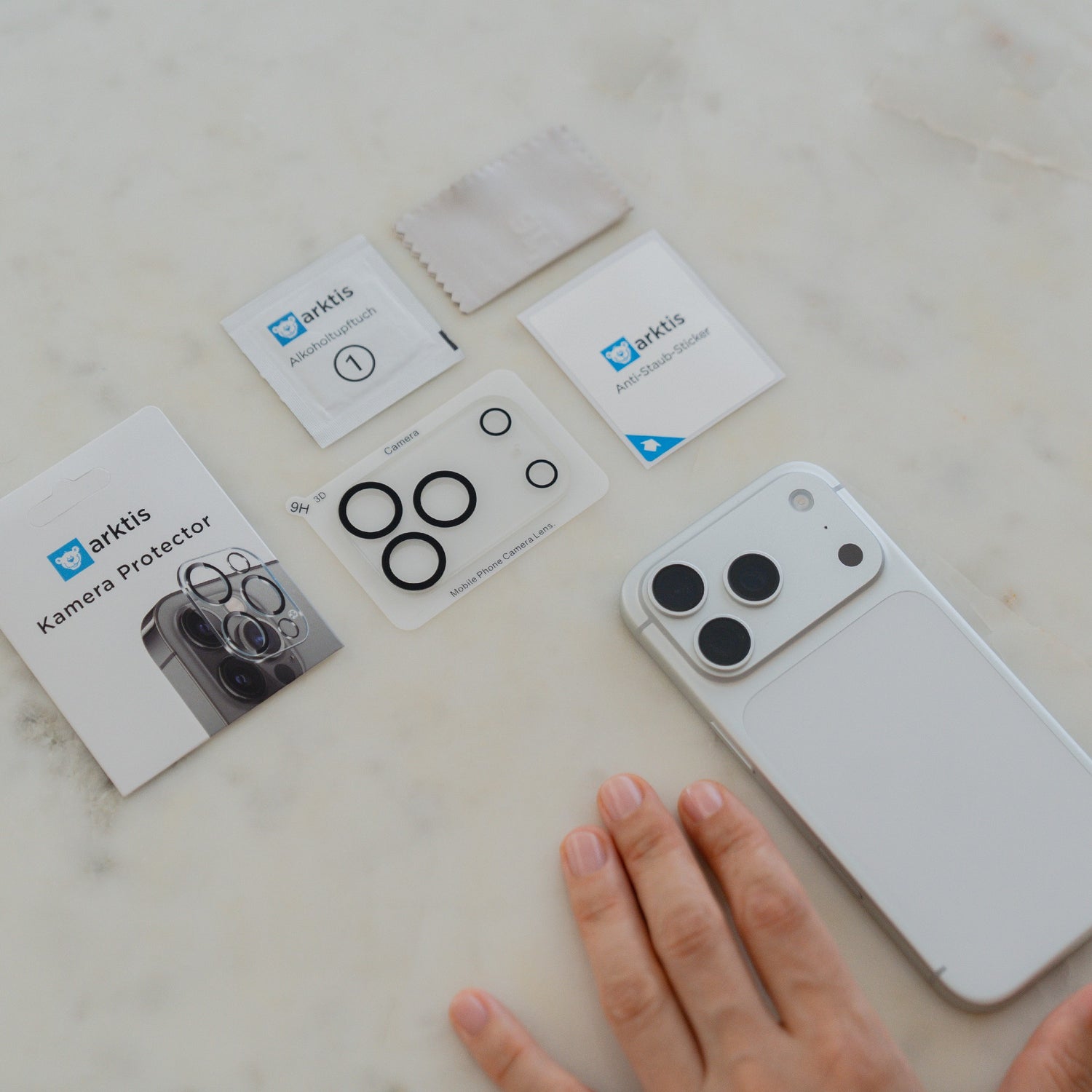 Eine Hand neben einem arktis iPhone 17 Pro Max Kamera Protector von arktis zeigt den Protector neben dem Kameraobjektiv.