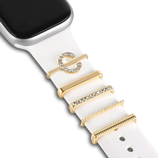 Ein weißes Smartwatch-Armband verfügt über fünf goldene und strassbesetzte Arktisband-Apple-Watch-Charms im „C-Stil“, darunter ein Buchstabe-C-Charm, vertikal angeordnet. Das Zifferblatt der Uhr wird oben links angezeigt. Perfekt für stylische Armbänder von artisband.