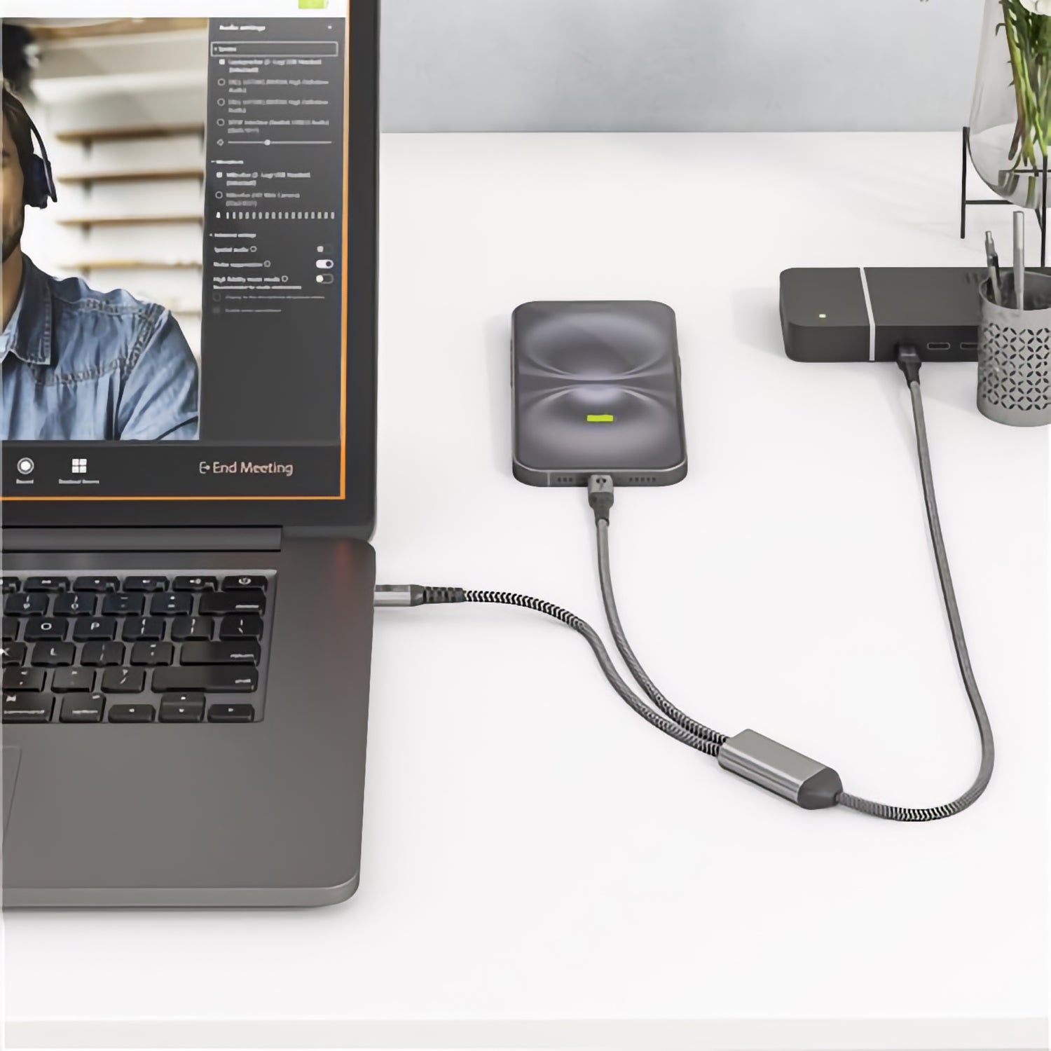 Ein goobay Dual USB-C auf USB-C Textilkabel mit Metallsteckern verbindet zwei externe Geräte am Laptop und sorgt für Hi-Speed-Datentransfer sowie 60 Watt Ladeleistung - ideal fürs effiziente Multitasking am weißen Schreibtisch.