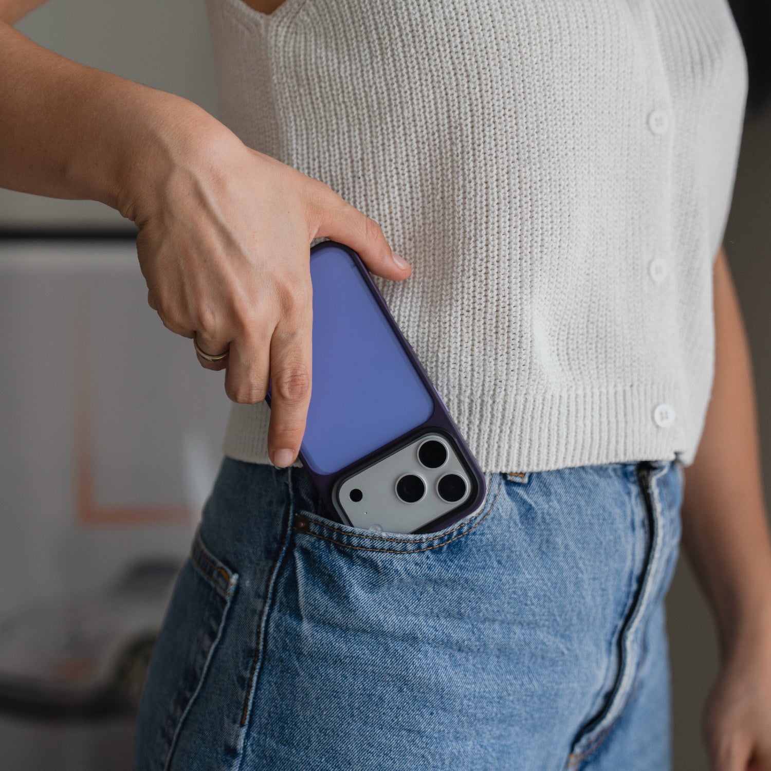 Eine Person in einem weißen Oberteil steckt ein Smartphone mit einem Arktis iPhone 17 Pro Solid Case in die Vordertasche einer blauen Jeans.