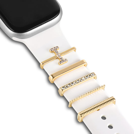 Eine Nahaufnahme einer Arktisband-Apple Watch mit weißem Armband zeigt vier vertikal angeordnete „I Style“-Arktisband-Anhänger aus Gold und Strass, wobei in der oberen linken Ecke ein Teil des Uhrenbildschirms und des Gehäuses sichtbar ist.