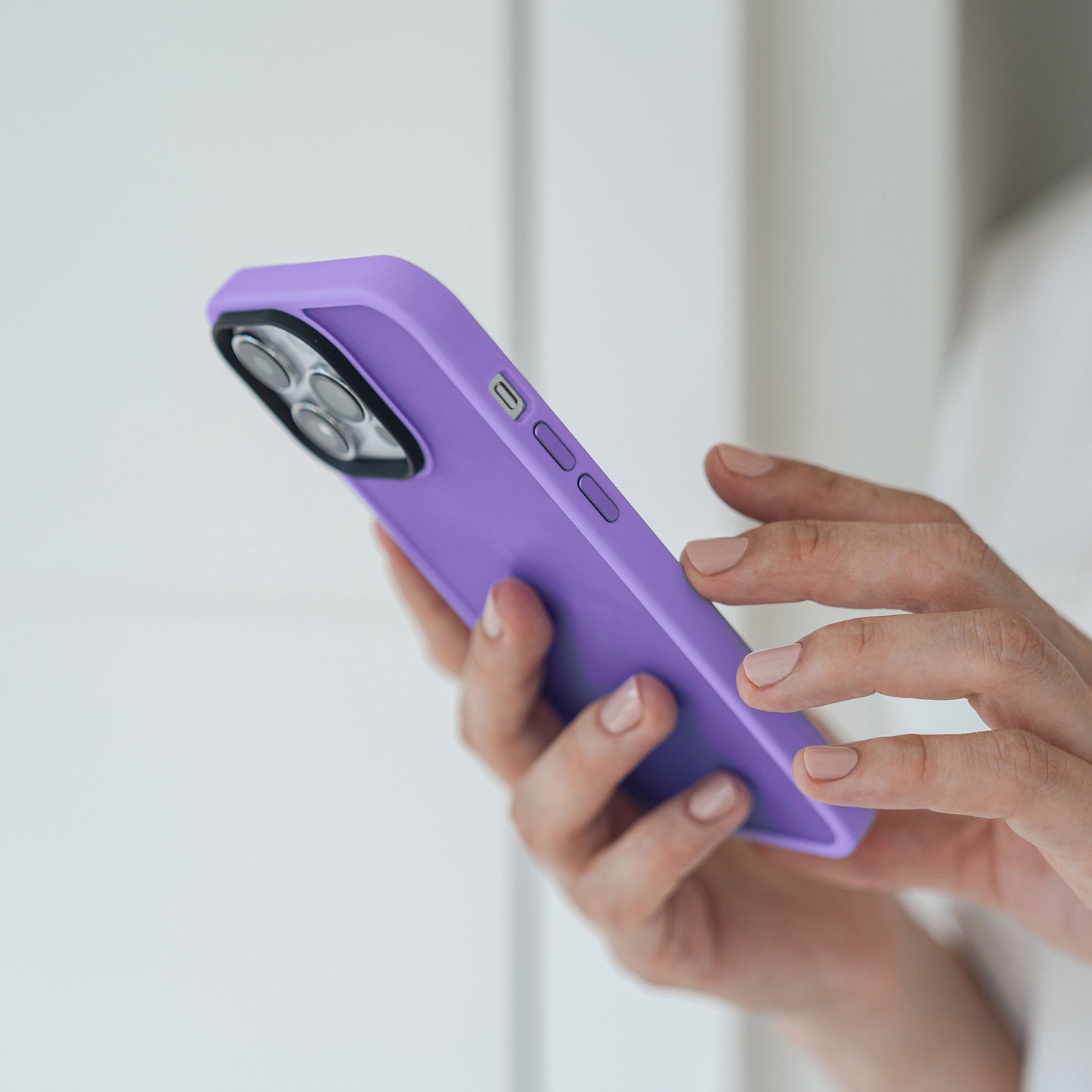 Eine Person hält und benutzt ein iPhone 13 Pro mit einem MR PROTECT iPhone 13 Pro Case Matt von MR PROTECT in der Nähe einer weißen Wand.