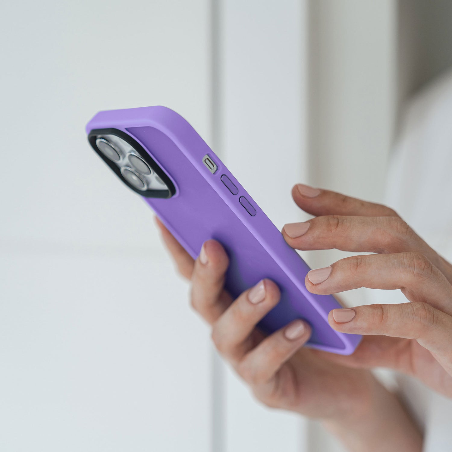 Eine Person hält und benutzt ein iPhone 13 Pro mit einem MR PROTECT iPhone 13 Pro Case Matt von MR PROTECT in der Nähe einer weißen Wand.
