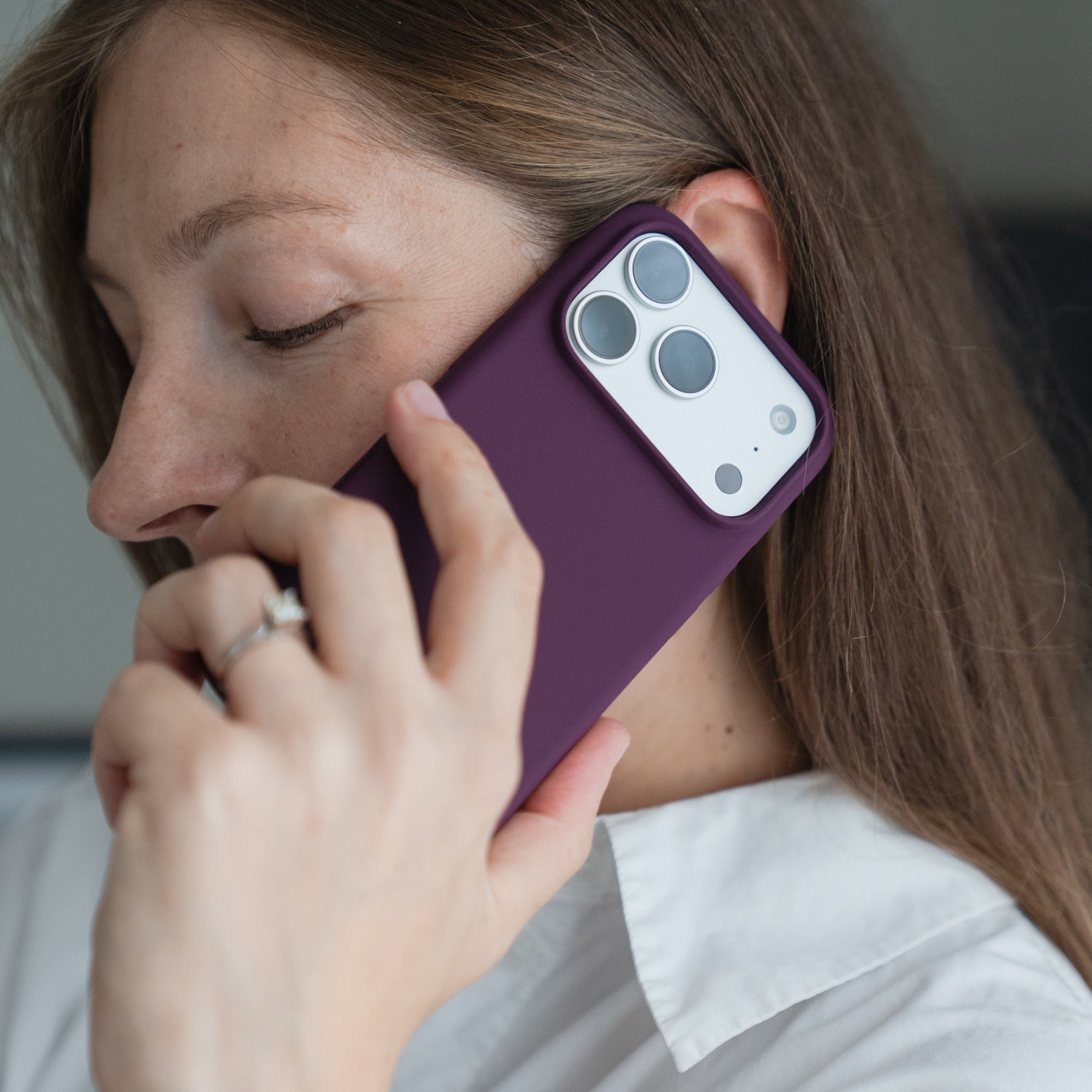 Eine Frau hält die Arktis iPhone 18 Pro Max Silikonhülle mit MagSafe in Burgunderrot in der Hand und trägt ein weißes Hemd sowie einen Ring.