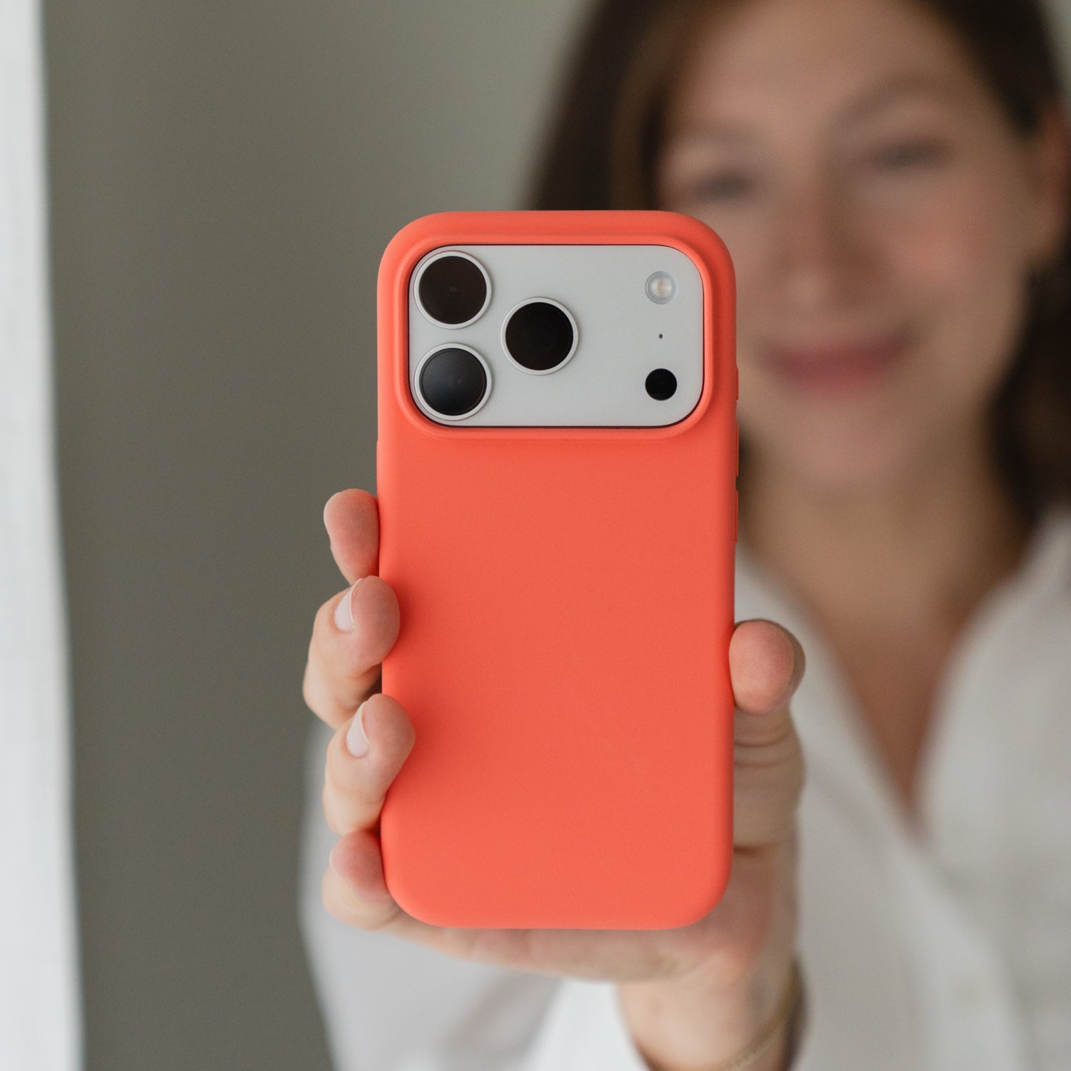 Eine Person in weißer Kleidung hält eine Arktis iPhone 18 Pro Max Silikonhülle mit MagSafe in Guavepink hoch, wobei die Kamera zum Betrachter zeigt.