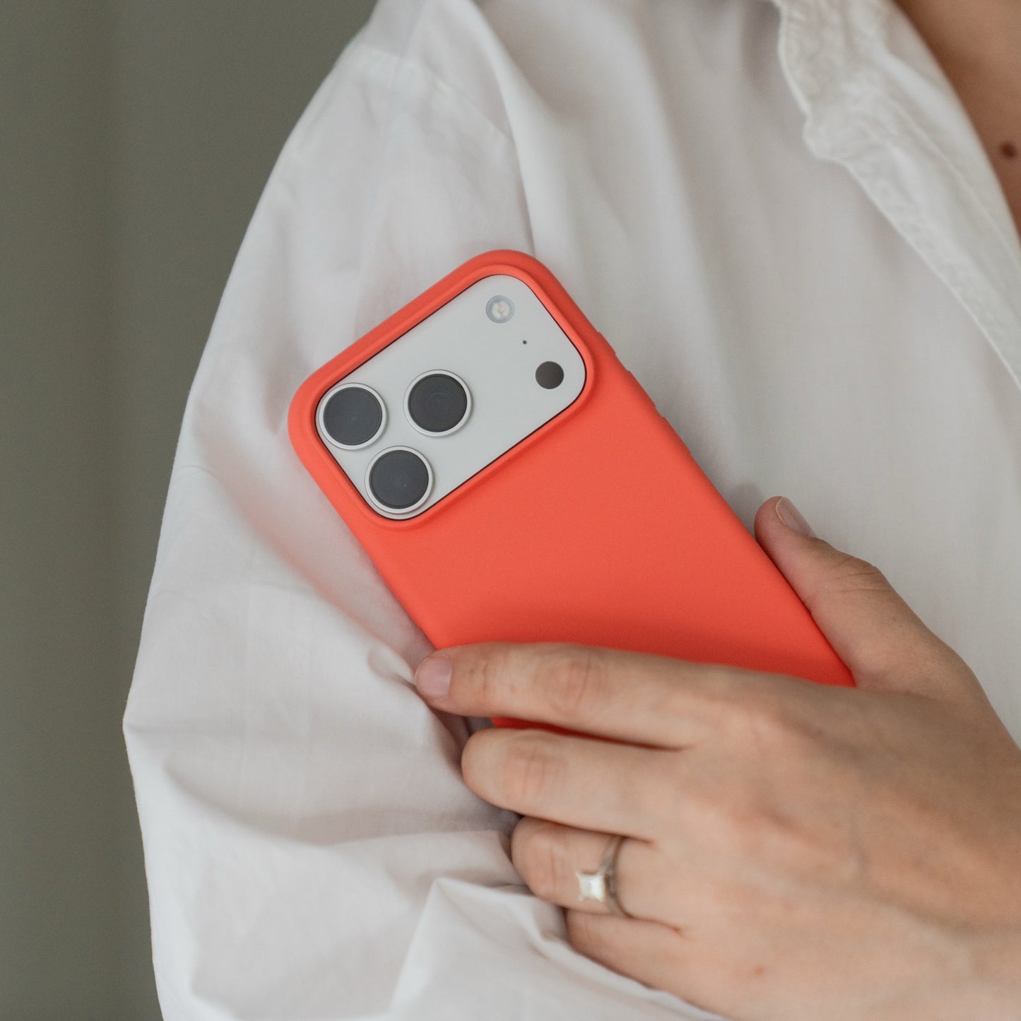 Eine Person hält eine Arktis iPhone 18 Pro Max Silikonhülle mit MagSafe in Guavepink in der Hand und trägt ein weißes Hemd sowie einen Ring.