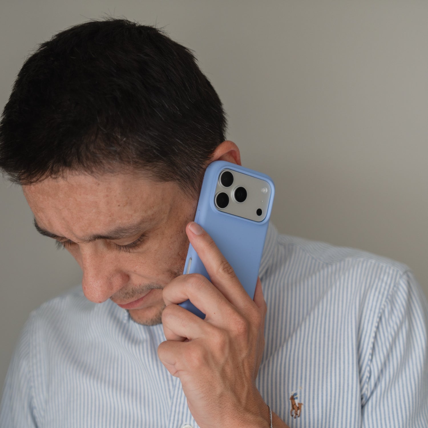Ein Mann, der eine Arktis iPhone 18 Pro Max Silikonhülle mit MagSafe Polar in der Hand hält und ein gestreiftes Hemd mit Logo trägt.