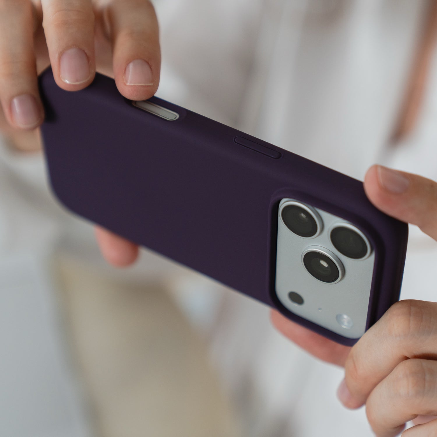 Hände halten eine arktis iPhone 18 Pro Max Silikonhülle mit MagSafe in Nebelviolett, wobei der Fokus auf den Kameralinsen liegt.