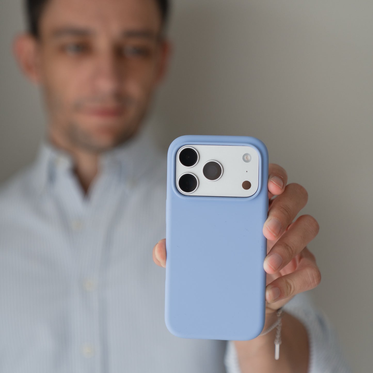 Eine Person in einem hellen Hemd hält eine Arktis iPhone 18 Pro Max Silikonhülle mit MagSafe Polar in der Hand, wobei die Linsen nach vorne zeigen.
