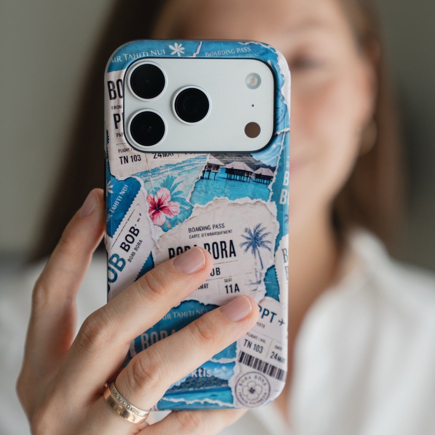 Person mit dem Arktis iPhone 16e – Happy Island in einer blauen Hülle mit tropischen Bordkarten und Palmen.