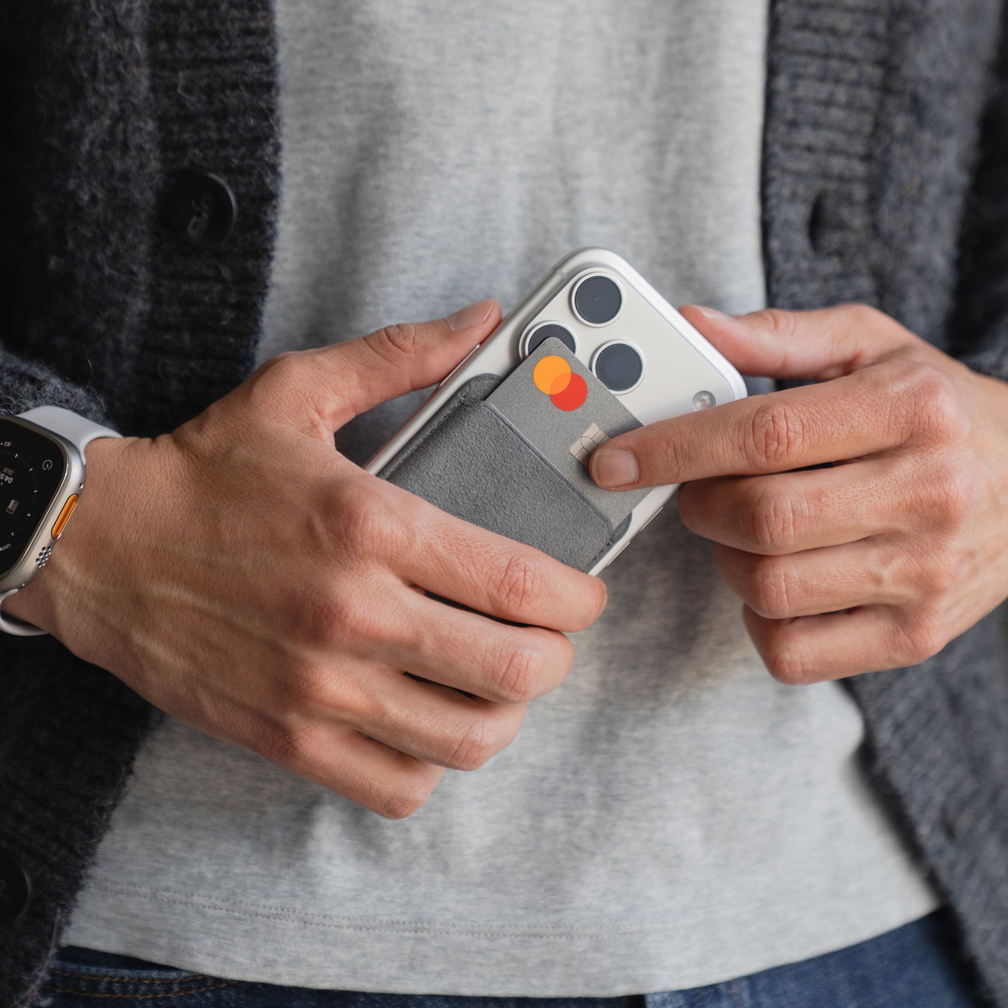 Eine Person entnimmt eine Karte aus einem arktis iPhone MagSafe Kartenhalter aus Alcantara, der auf der Rückseite eines iPhones angebracht ist.