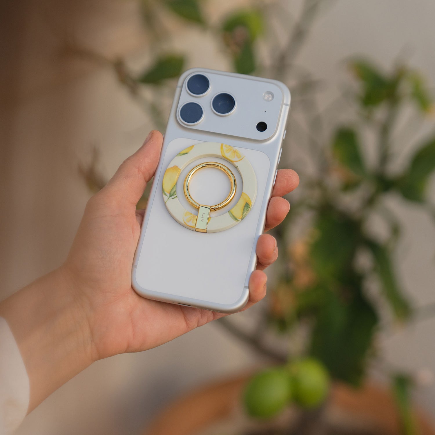 Eine Hand hält ein weißes Smartphone, auf dessen Rückseite der arktis Magnetischer Ringhalter für MagSafe - Sweet Leopard angebracht ist, was es zu einem stylischen iPhone Zubehör macht.