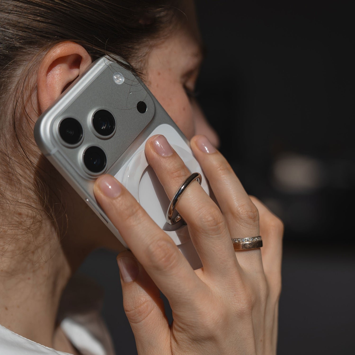 Eine Person hält ihr Smartphone mit dem arktis Magnetischer Ringhalter für MagSafe - Sweet Leopard an ihr Ohr und konzentriert sich dabei auf ihre Hand und das Telefon während eines Anrufs.