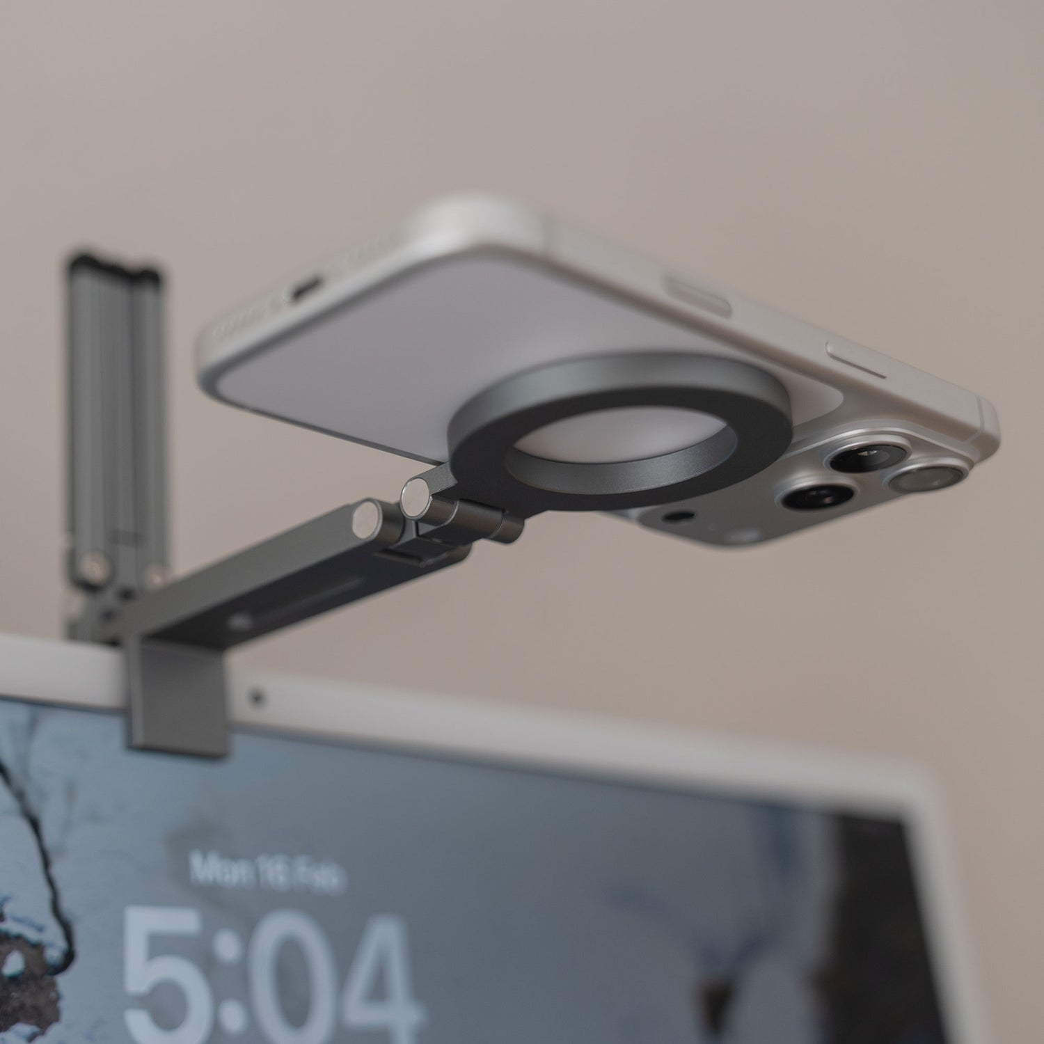 Die arktis iPhone MagSafe Tripod 360 Halterung von arktis, montiert an der Oberkante eines Computermonitors, hält ein Smartphone und kann um 360° gedreht werden.