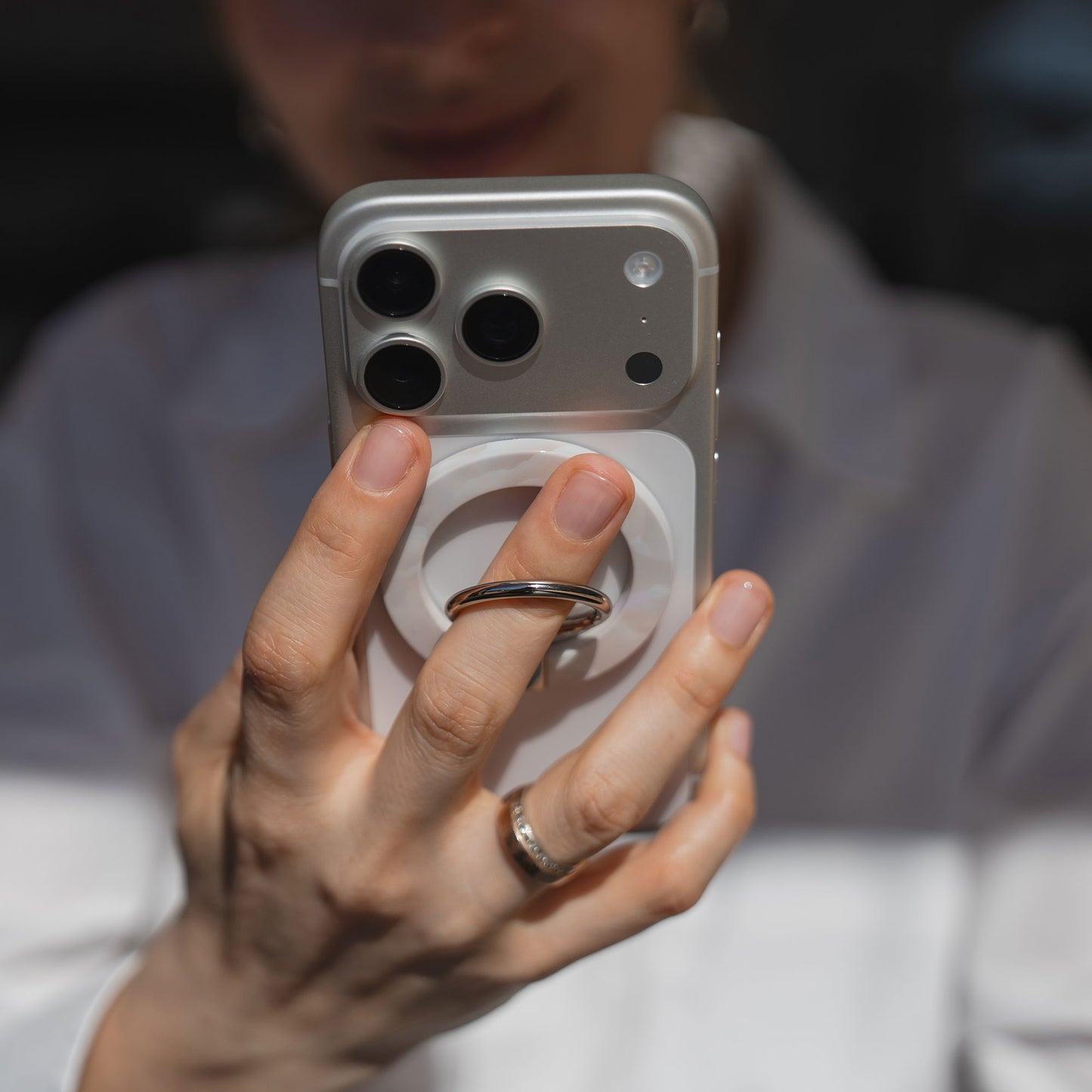 Eine Person hält ein Smartphone mit dem arktis Magnetischer Ringhalter für MagSafe - Sweet Leopard, mit starken N52 Magneten, die auf der Rückseite für einen sicheren Halt sorgen.