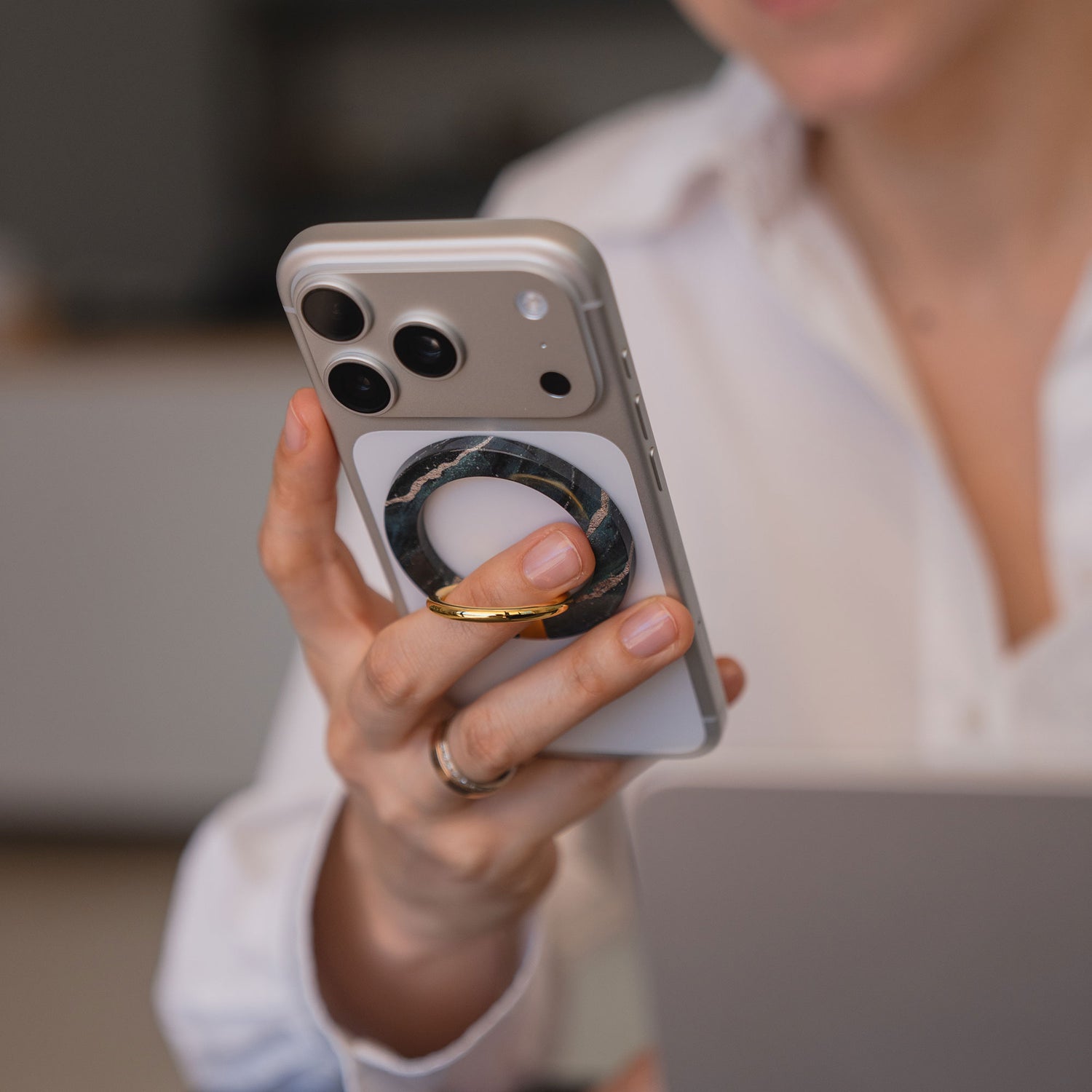 Eine Person hält ein Smartphone mit dem arktis Magnetischer Ringhalter für MagSafe - Sweet Leopard, trägt ein weißes Hemd und einen goldenen Ring.