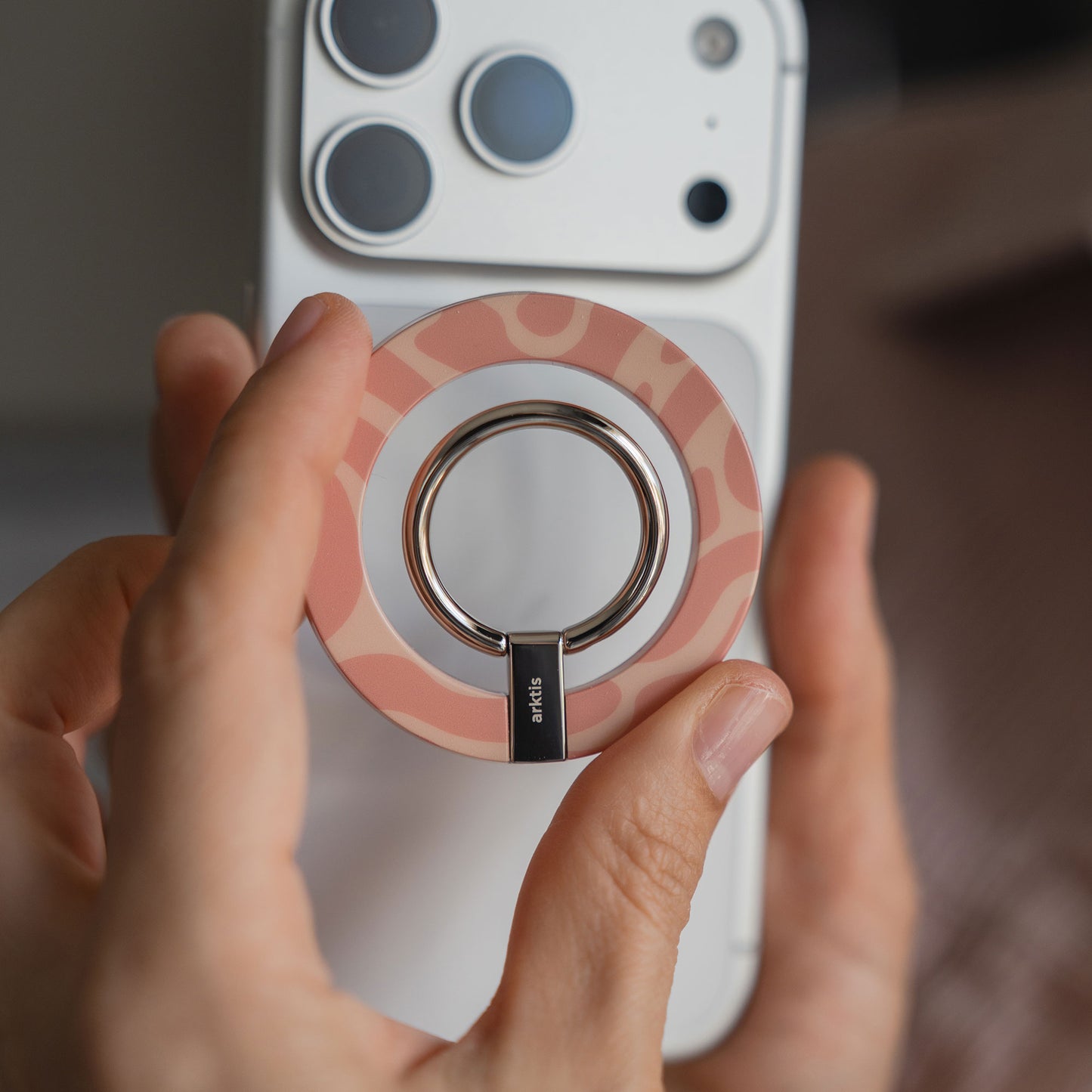Eine Hand hält den arktis Magnetischer Ringhalter für MagSafe - Sweet Leopard, der an einem weißen Smartphone befestigt ist und stylisches iPhone Zubehör mit starken N52 Magneten für sicheren Halt bietet.