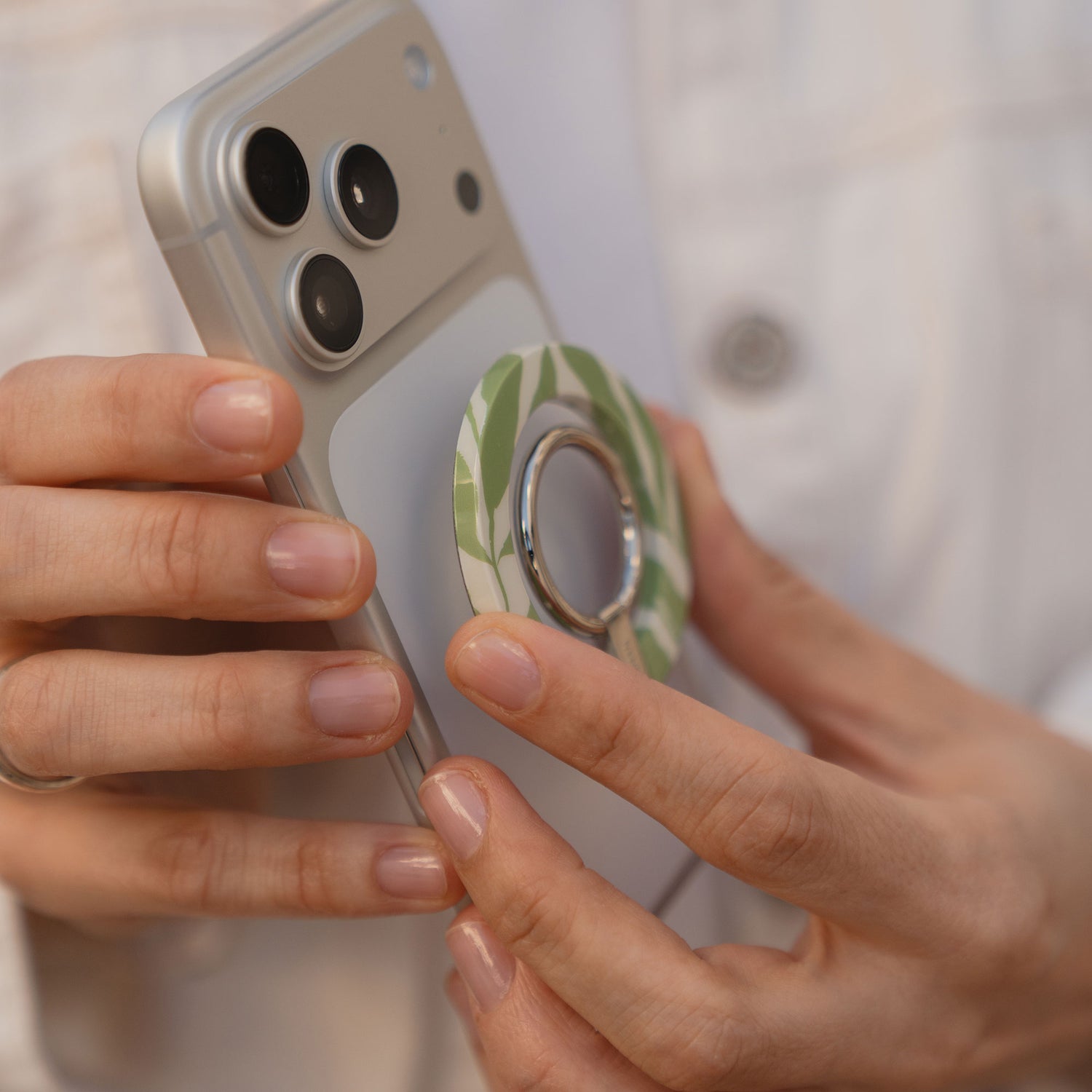 Jemand hält ein Smartphone mit dem arktis Magnetischer Ringhalter für MagSafe - Botanic auf der Rückseite und macht daraus ein stylisches iPhone Zubehör.