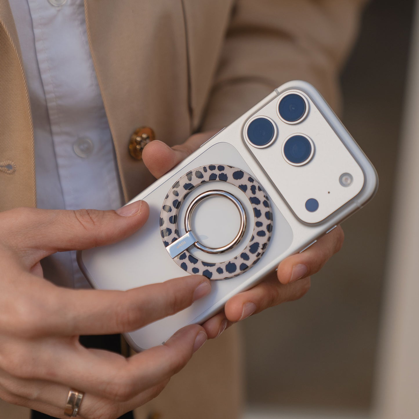 Eine Person hält ein weißes Telefon mit dem arktis Magnetischer Ringhalter für MagSafe - Sweet Leopard auf der Rückseite und hebt dieses stylische iPhone Zubehör mit starken N52 Magneten hervor.