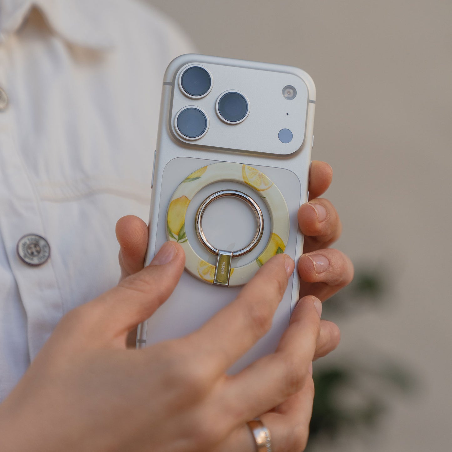 Person hält ein weißes Telefon mit dem arktis Magnetischer Ringhalter für MagSafe - Sweet Leopard angebracht-stylisches und praktisches iPhone Zubehör für sicheren Halt.