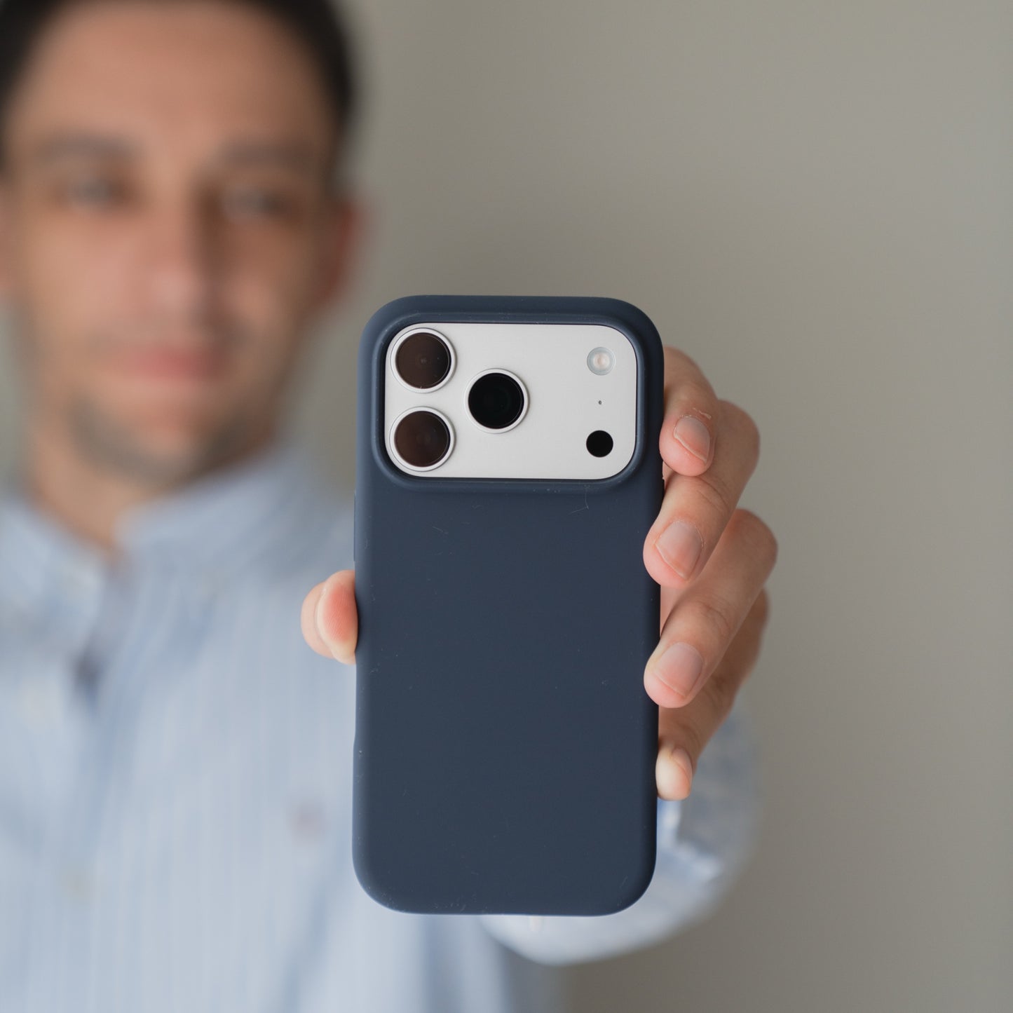Eine Person hält eine Arktis iPhone 18 Pro Max Silikonhülle mit MagSafe in Mitternacht in der Hand, während das Gesicht im Hintergrund unscharf ist.