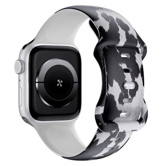 Das arktisband Kuhfell Apple Watch Armband zeigt einen schwarz-weißen Kuhdruck auf Silikon, hier auf einer silbernen Apple Watch in der schrägen Seitenansicht - ideal für sportliche Aktivitäten.