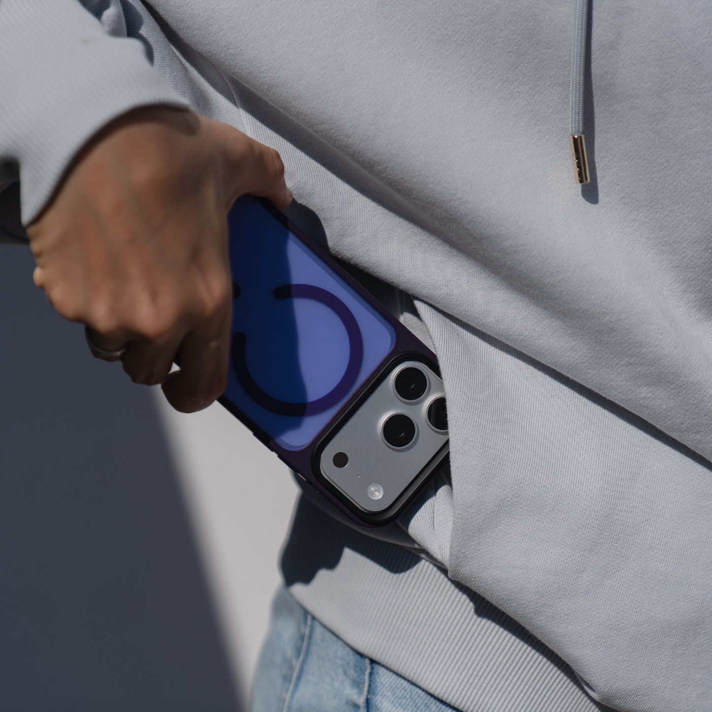 Eine Person steckt ein Arktis iPhone 17 Pro Solid Case mit MagSafe von Arktis in die Tasche einer hellblauen Jeans.
