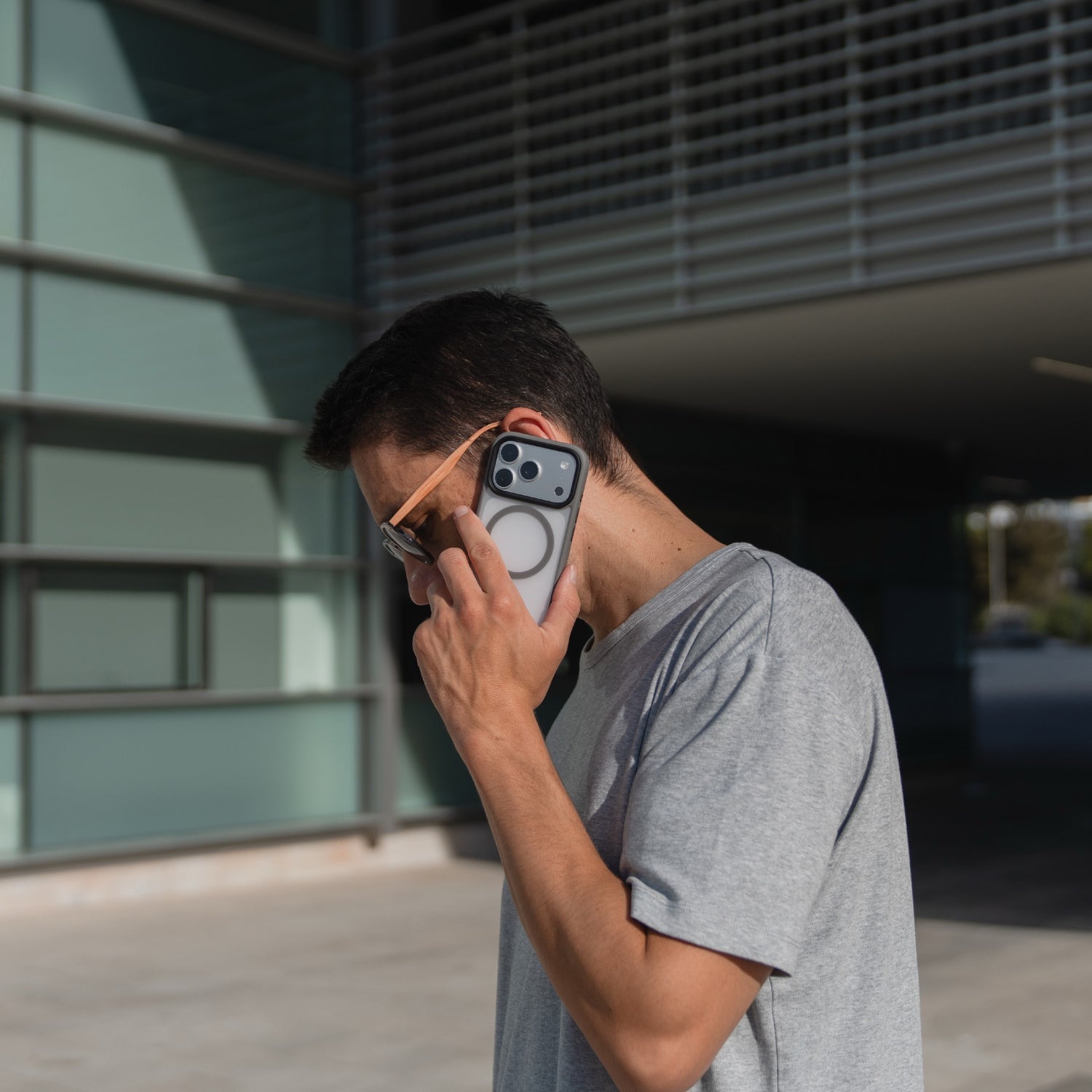 Ein Mann mit Sonnenbrille steht vor einem modernen Gebäude und hält ein Smartphone mit dem Arktis iPhone 17 Pro Solid Case mit MagSafe an sein Ohr.