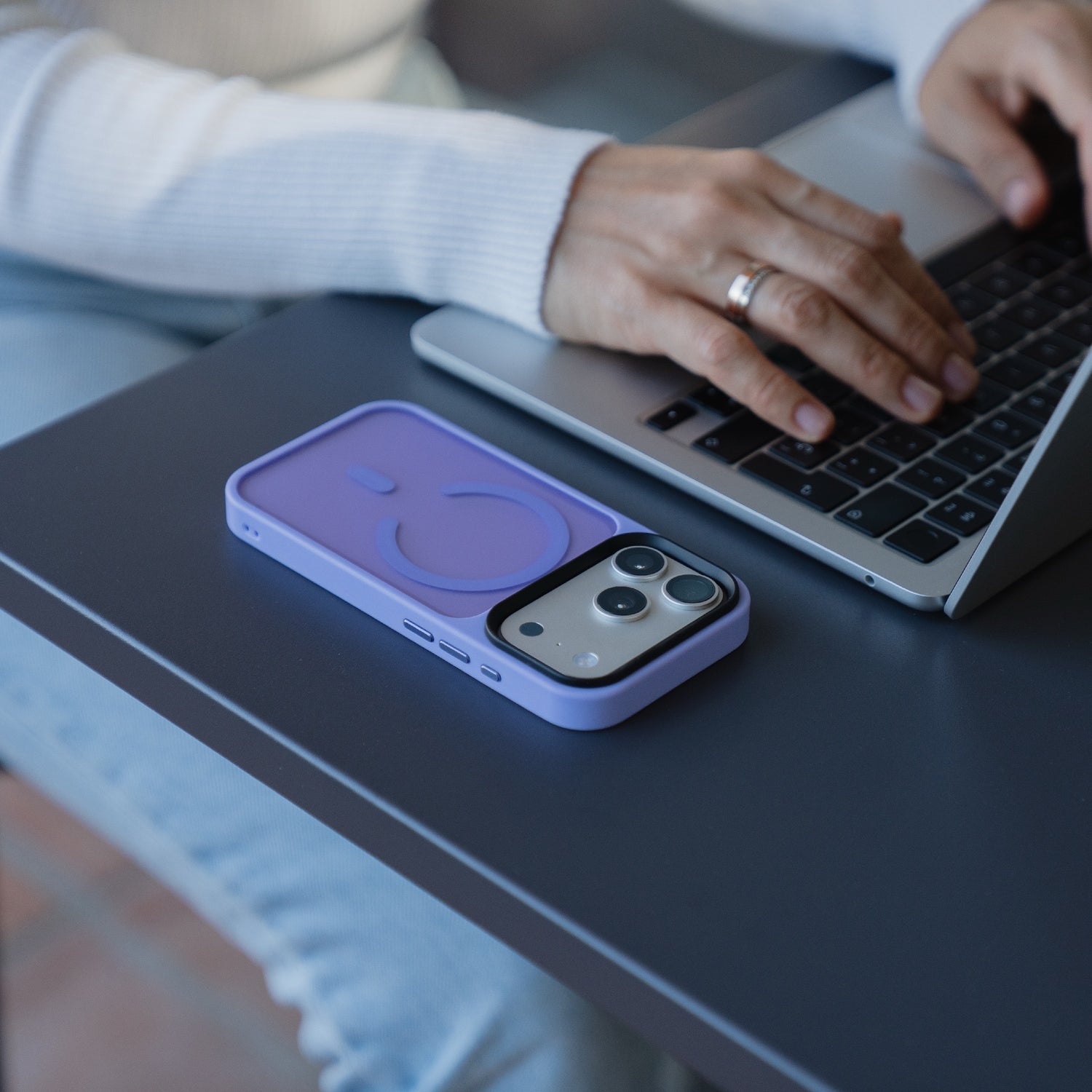 Jemand tippt auf einem Laptop, während in der Nähe ein Arktis iPhone 17 Pro Solid Case mit MagSafe mit mattem Finish liegt.