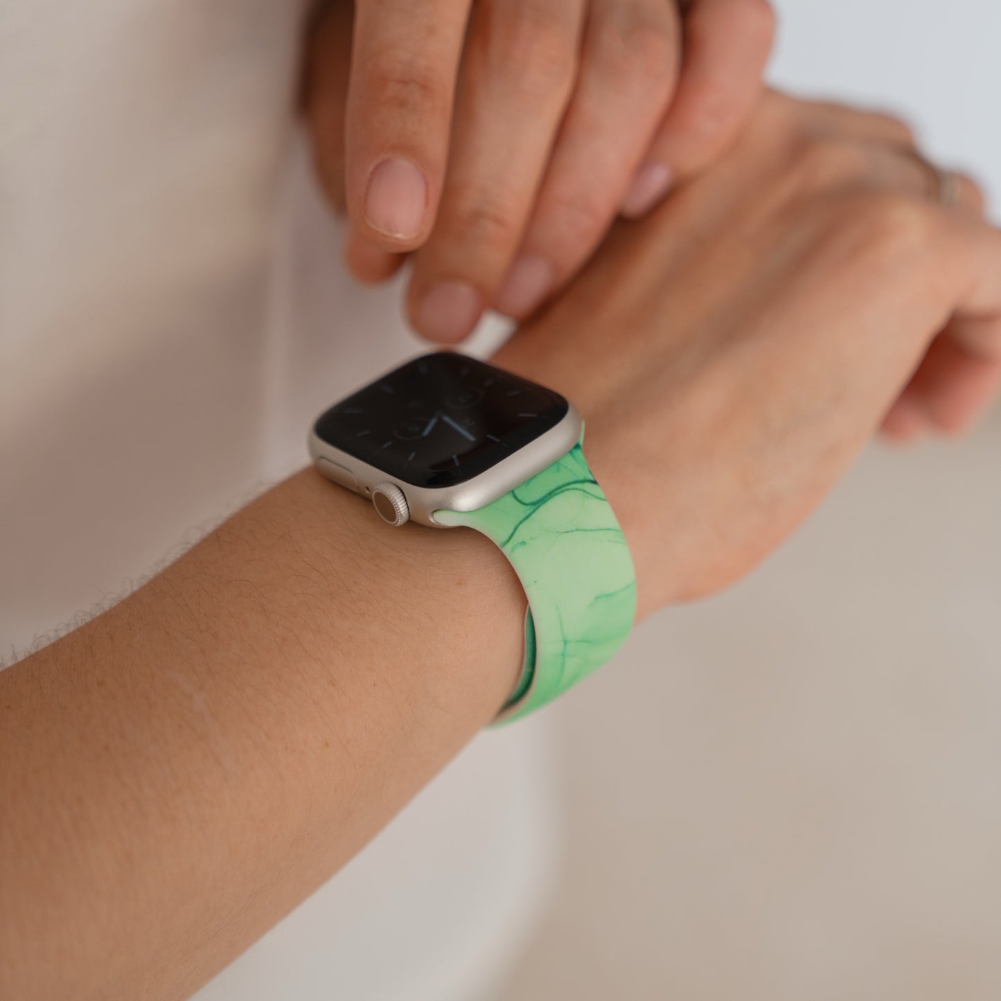 Nahaufnahme einer Person, die ein arktisband Green Marble Apple Watch Armband von arktisband an ihrem Handgelenk trägt.