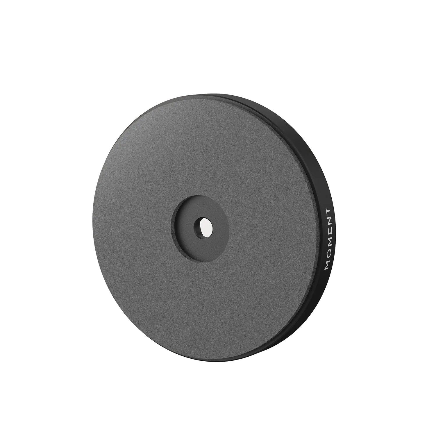 Die MOMENT Wandhalterung für MagSafe ist eine runde, schwarze, flache Magnetscheibe mit einem zentralen Loch und MOMENT am Rand - ideal als MagSafe Wandhalterung für Ihre Geräte.