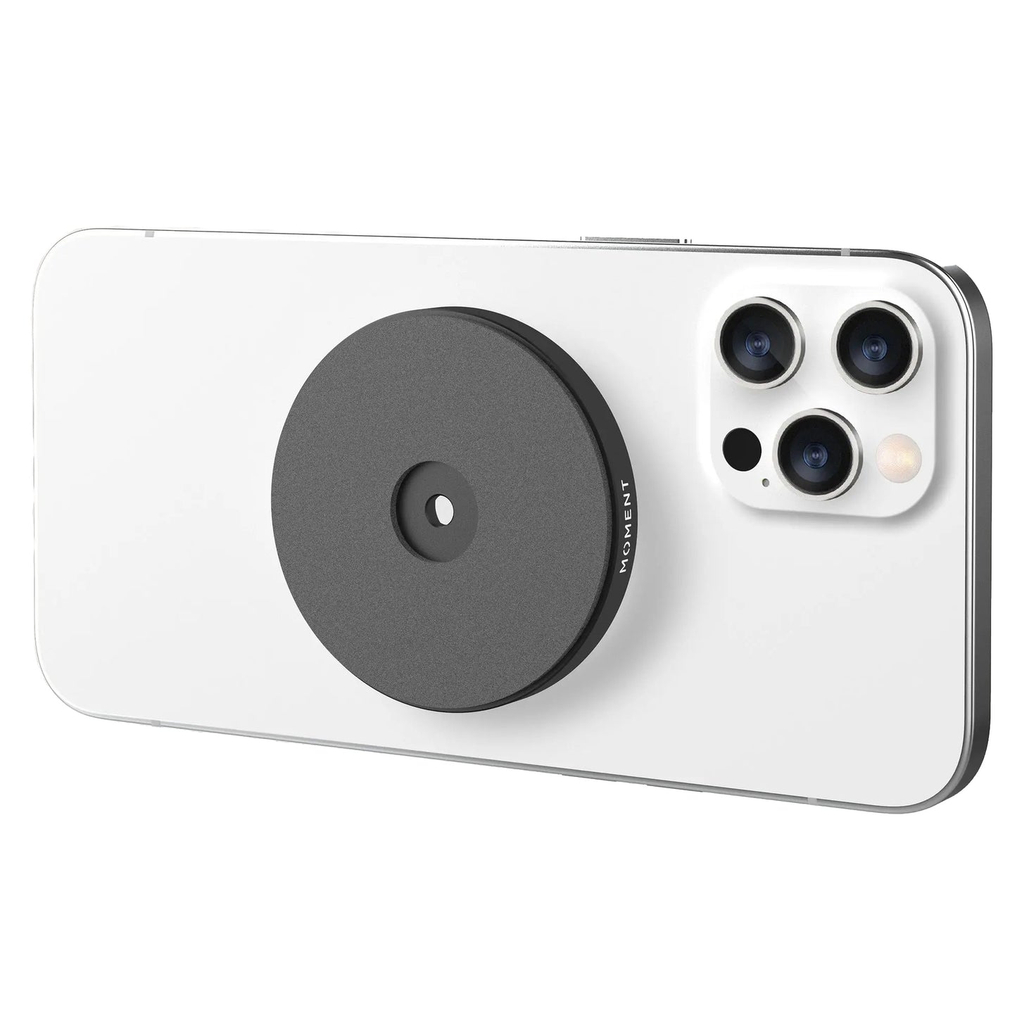 Ein weißes Smartphone mit einer MOMENT Moment Wall Mount für MagSafe (schwarz, rund), die in der Nähe des dreifachen Kameramoduls auf der Rückseite angebracht ist.