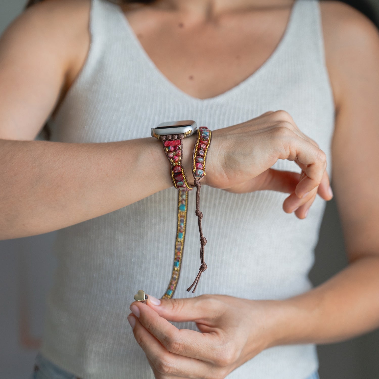 Eine Person befestigt das Arktisband Apple Watch Armband "Dream Catcher" mit Edelstahladapter an ihrem Handgelenk und unterstreicht damit den schicken Boho-Stil.